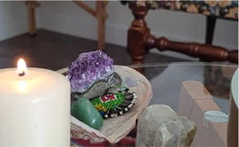 Bougie rituelle, améthyste brute et pierre d'aventurine verte sur une table